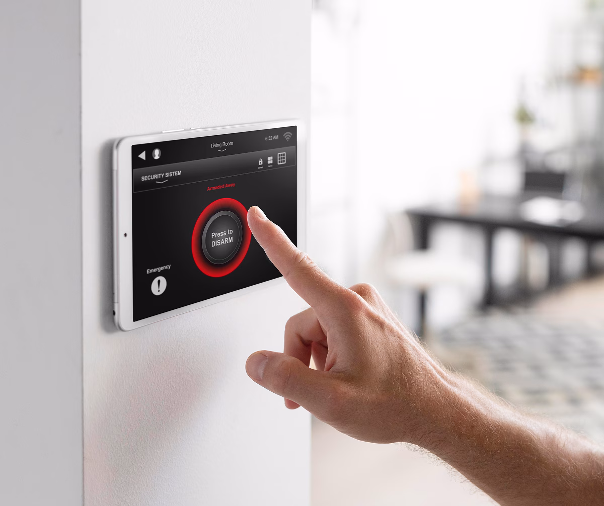Person pressing a red button on a wall-mounted alarm panel