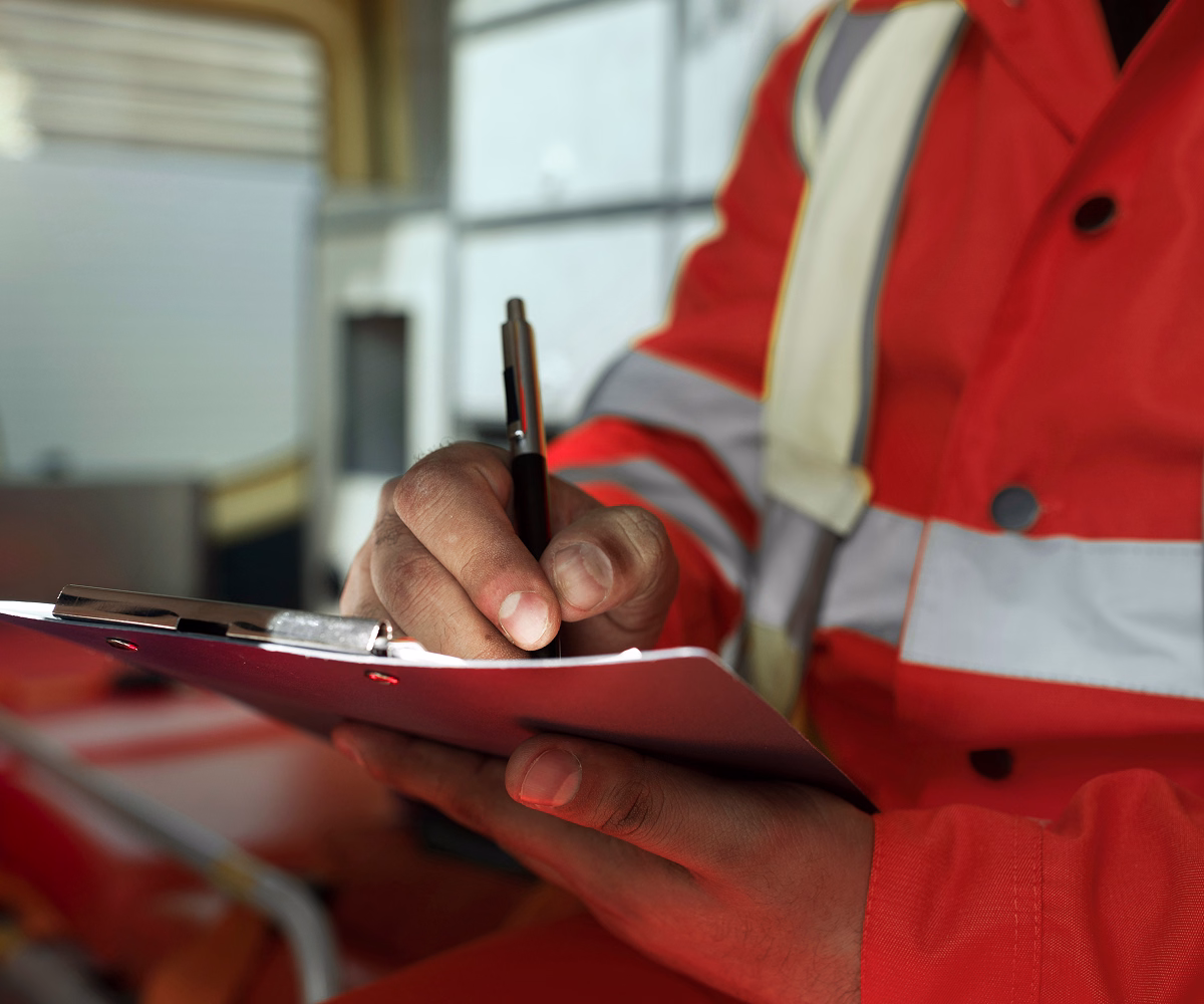 Technician wearing a high-visibility vest completing an inspection checklist