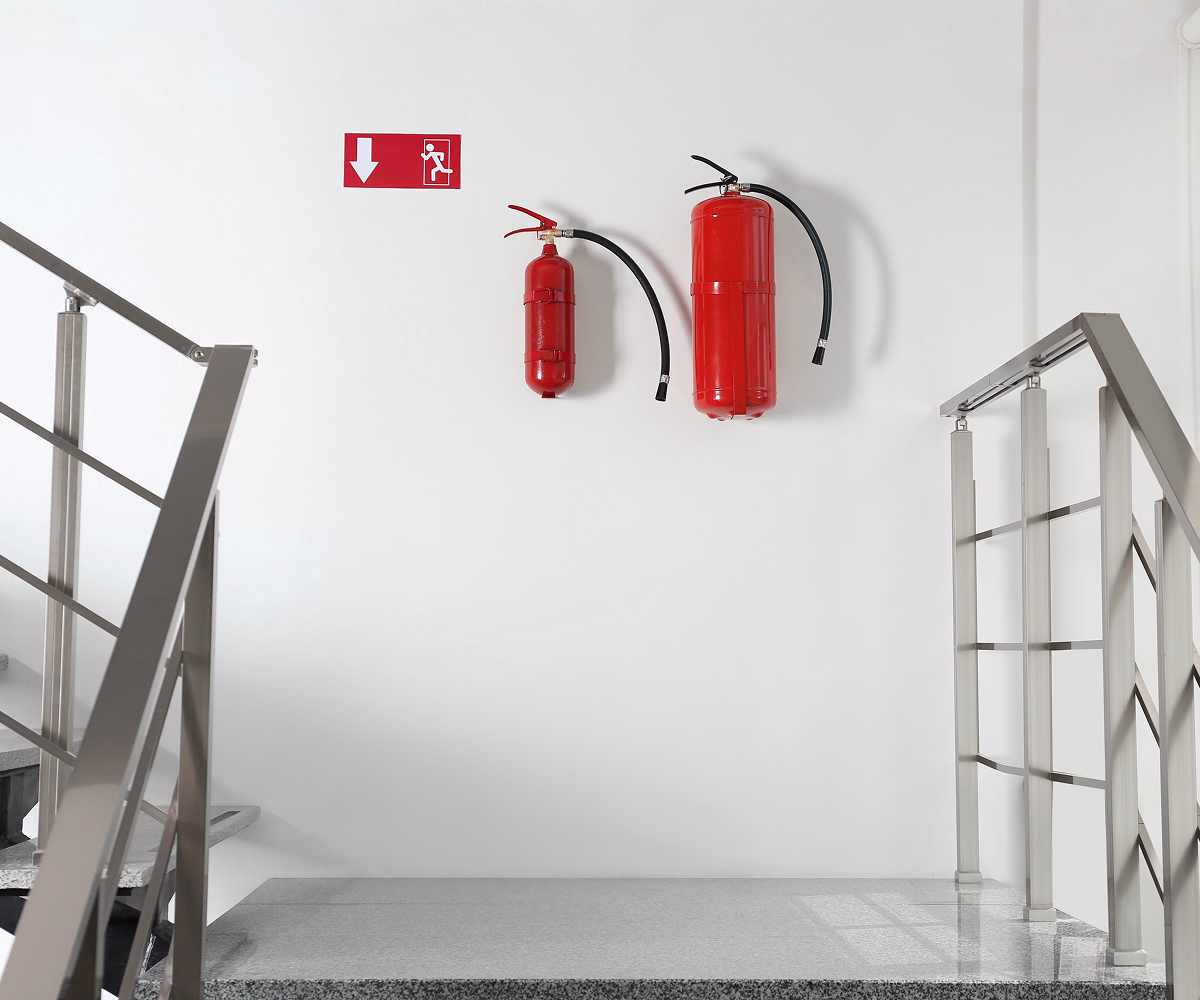 Two fire extinguishers mounted at a stair landing